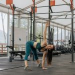 Caucasian woman stretching in a modern gym environment, promoting fitness and exercise.